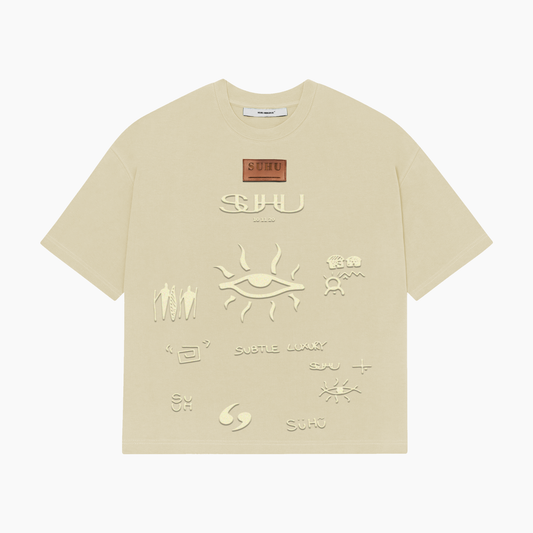 A beige SUHU t-shirt with various text and symbol embossments on the front, featuring the puff print SUHU symbols.