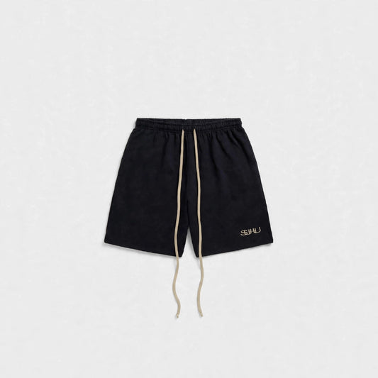Black luxury shorts with a beige drawstring and a small gold logo on the lower left leg, displayed flat against a light gray background.